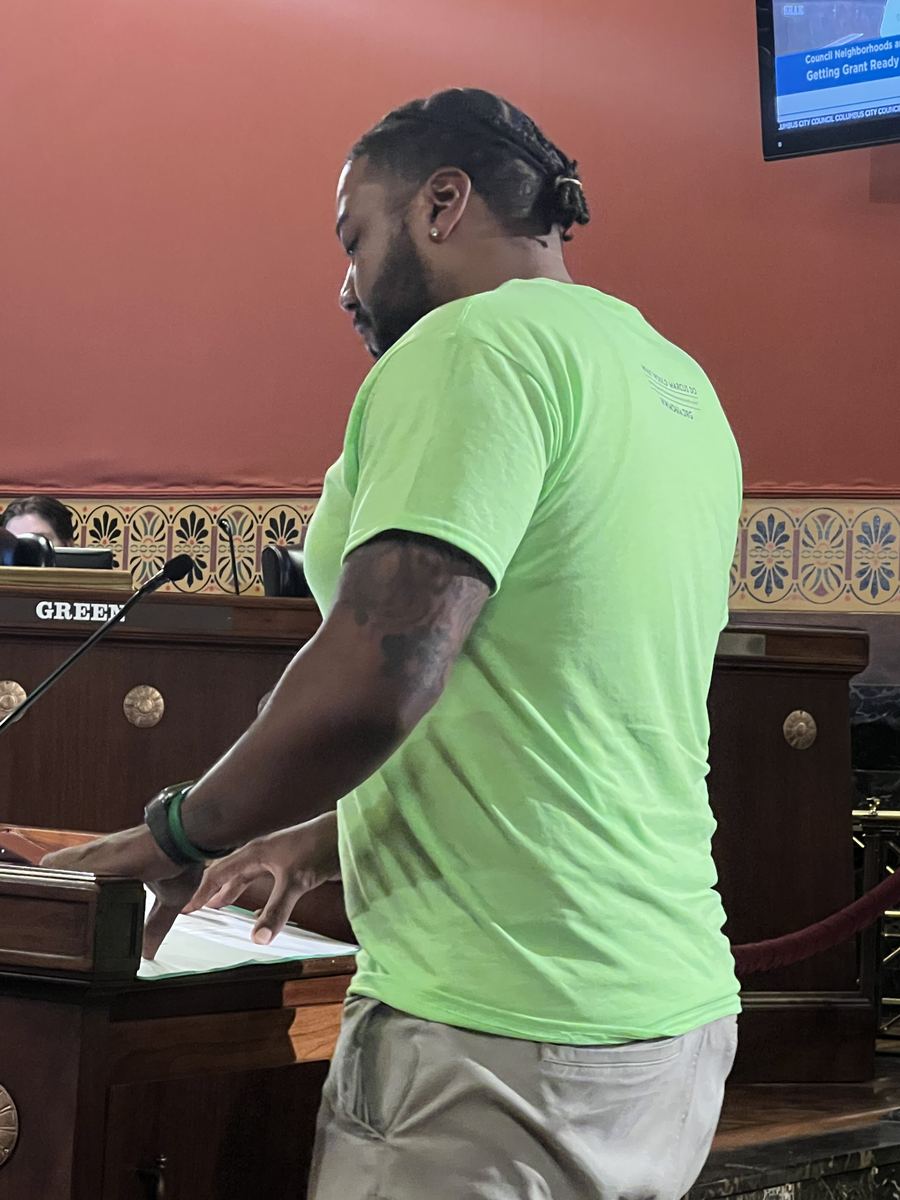 A person reading prepared remarks at a lectern in a public meeting room.