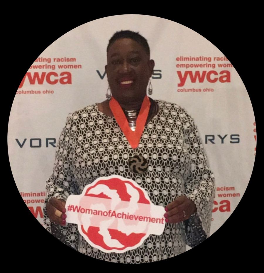 Fredericka Wallace Deena standing at a microphone in front of a backdrop.